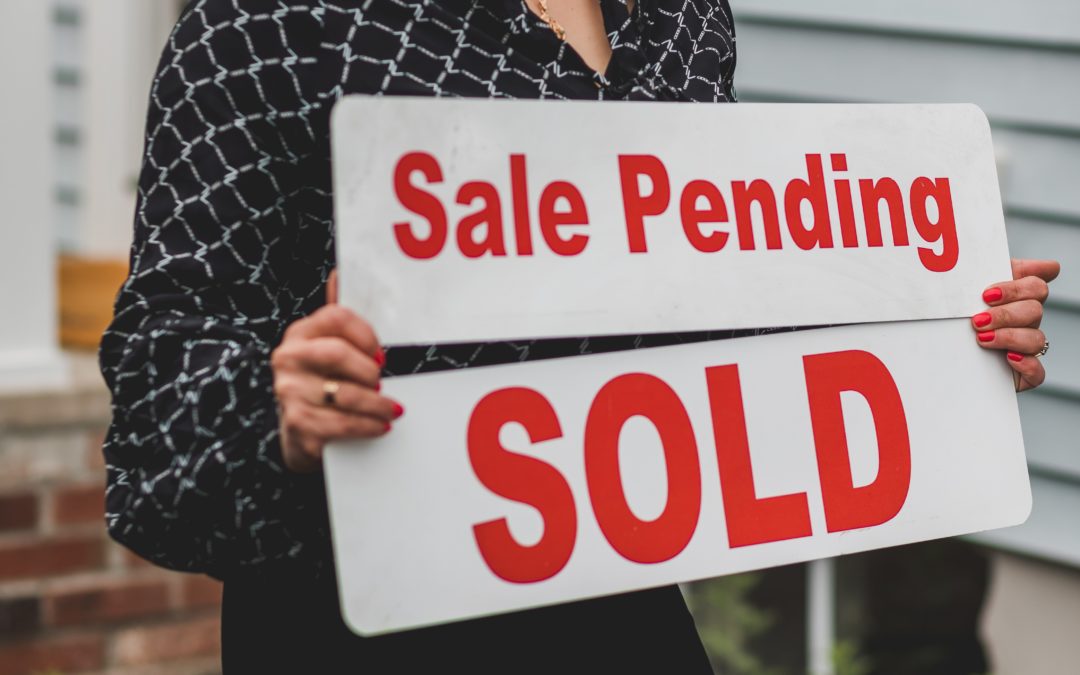 Real estate agent holding Sale Pending Sold sign